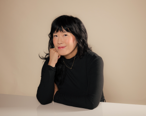 Photo of author Eileen Lee sitting a table smiling at the camera