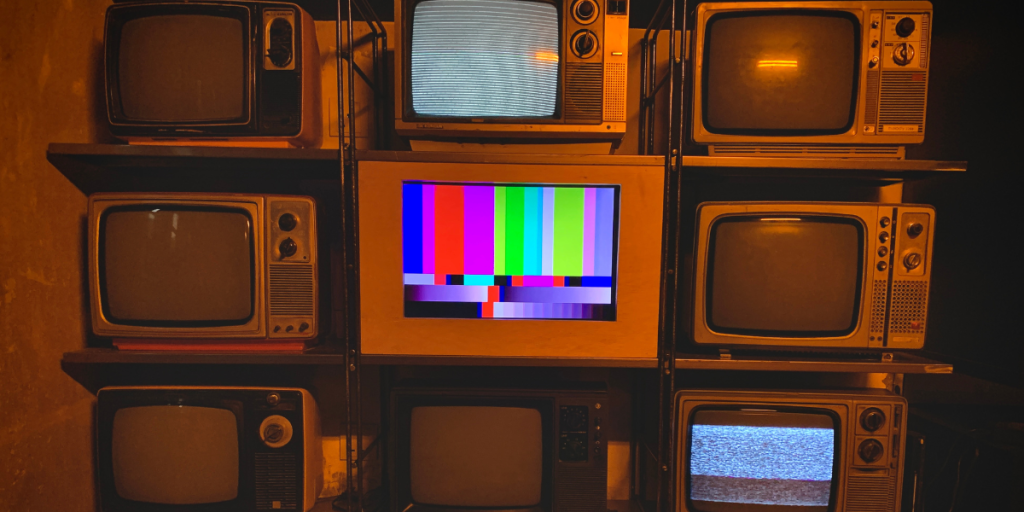 TVs stacked on top of one another with one glowing in the middle